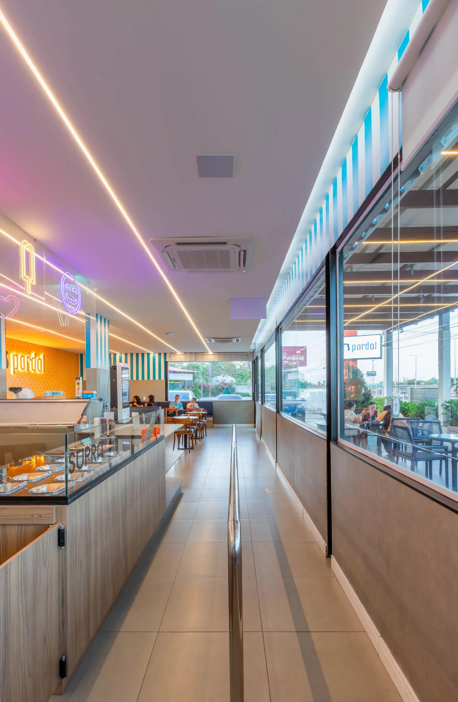 Salão da sorveteria Pardal com balcão de gelatos, corredor central e vitrine voltada para a área externa com clientes