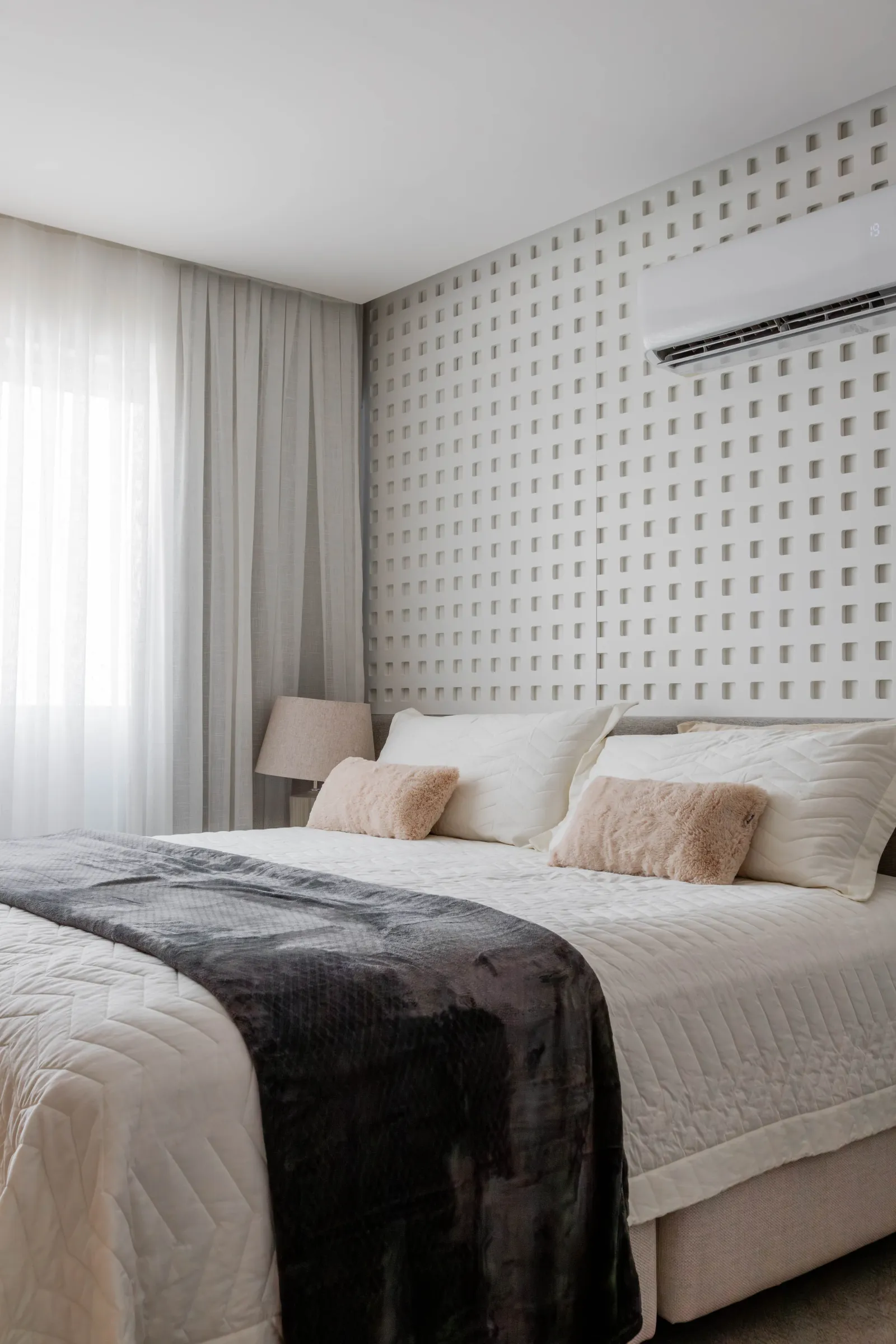 Quarto de casal do Residencial ML com cabeceira em cobogó branco, cortinas claras, roupa de cama branca com manta cinza e almofadas rosé