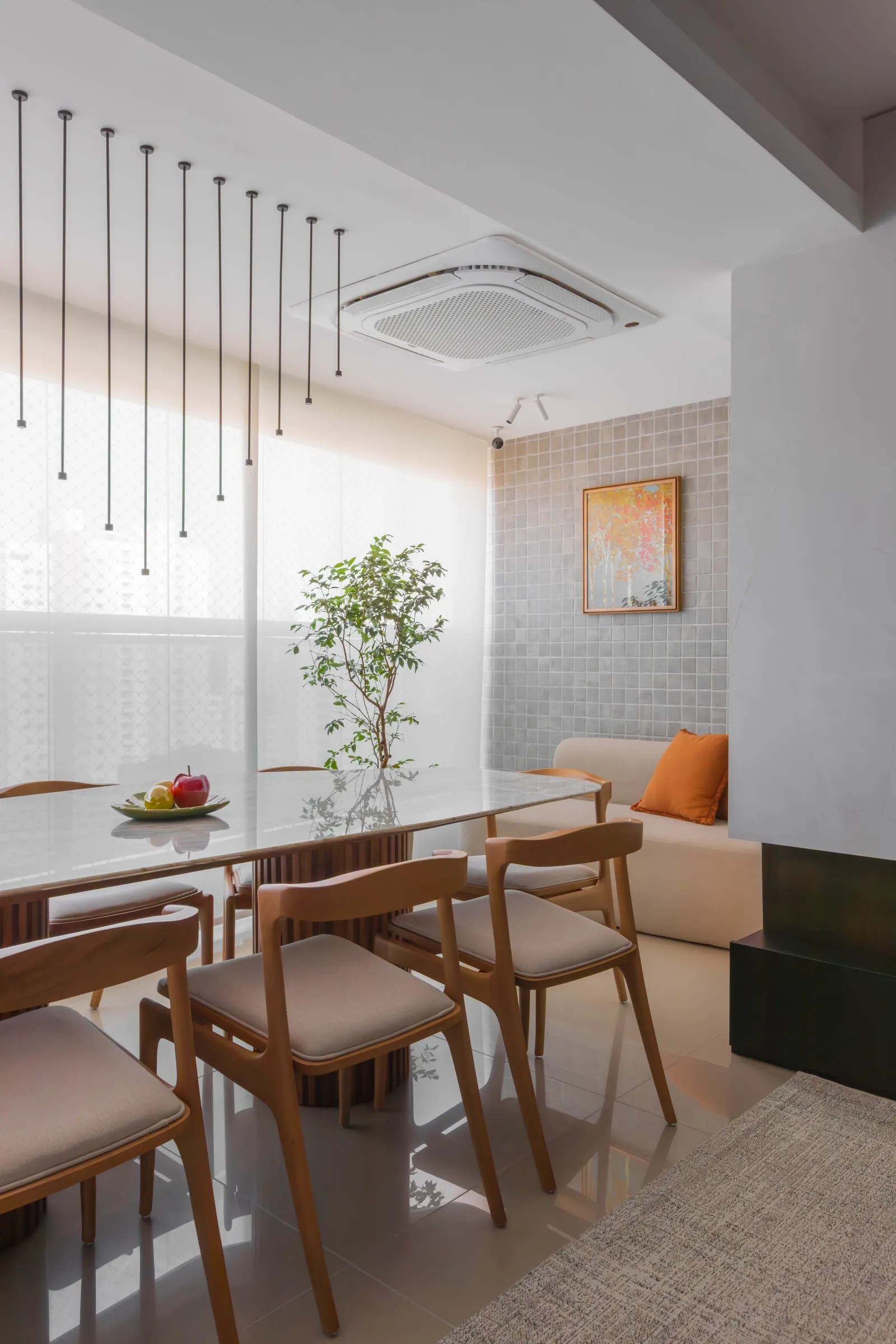 Sala de jantar do Residencial TN com mesa de tampo de pedra, cadeiras de madeira, pendentes lineares suspensos e integração com o living ao fundo
